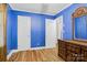 Bright bedroom featuring hardwood floors, blue walls, and a rustic wooden dresser with ornate mirror at 1116 Crestview Dr, Salisbury, NC 28146