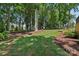 Lush backyard with mature trees and a meticulously maintained lawn with a stone patio at 122 Ringneck Trl, Mooresville, NC 28117