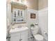 Cozy bathroom with a white vanity, toilet, mirror, and warm beige walls with a view into the kitchen at 122 Ringneck Trl, Mooresville, NC 28117