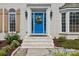 Close-up of a blue front door with a decorative wreath, sidelights, and stone steps, framed by manicured landscaping at 122 Ringneck Trl, Mooresville, NC 28117