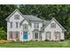 Elegant, two-story brick home features a bright blue front door, manicured lawn, and mature trees at 122 Ringneck Trl, Mooresville, NC 28117