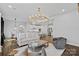 Living room with modern chandelier, white sofa, and dark-colored chair with a view into the kitchen and dining area at 12615 Es Draper Dr, Huntersville, NC 28078