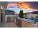 Outdoor kitchen area next to the in-ground pool and lovely backyard at sunset at 12615 Es Draper Dr, Huntersville, NC 28078
