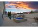 An inviting backyard offers a pristine pool, hot tub, lounge area, and dining space under a colorful evening sky at 12615 Es Draper Dr, Huntersville, NC 28078