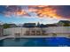 Sparkling pool featuring lounge chairs, umbrellas, and fire bowls, set against a vibrant sunset backdrop at 12615 Es Draper Dr, Huntersville, NC 28078