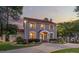 Beautiful home at dusk with gray siding and a red tile roof, professional landscaping, a gated driveway, and exterior lighting at 1619 Providence Rd, Charlotte, NC 28207