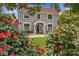 Charming two-story home with gray siding, a red tile roof, and a beautiful landscaped front yard with mature trees and rose bushes at 1619 Providence Rd, Charlotte, NC 28207