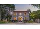 Beautiful home at dusk with gray siding and a red tile roof with professional landscaping and a gated driveway at 1619 Providence Rd, Charlotte, NC 28207