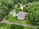 An aerial view shows a house, pool, patio, and abundant greenery in the surrounding landscape at 175 Turnberry Ln, Mooresville, NC 28117