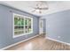 Cozy bedroom with light blue walls, wood floors, a ceiling fan, and a large window at 176 Sharon Valley Dr, Hickory, NC 28601
