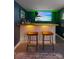 Finished basement bar area with a white wooden bar, entertainment center, and two leather cushioned barstools at 1826 Hall Ave, Charlotte, NC 28205