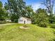 Large backyard featuring a detached garage, fire pit, and mature trees creating a private oasis at 2136 W 6Th Ave, Gastonia, NC 28052