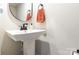 Powder room featuring pedestal sink, round mirror, towel and modern faucet at 2203 Autumn Olive Ln, Stallings, NC 28104