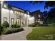 Night view of an elegant white brick home with landscaped front yard and a stone walkway to the entrance at 2215 Cortelyou Rd, Charlotte, NC 28211