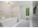 Main bathroom features a soaking tub, glass shower, marble floors and large window at 2215 Cortelyou Rd, Charlotte, NC 28211