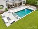 Stunning backyard pool with lounge area, covered patio, outdoor kitchen and beautifully manicured lawn at 2215 Cortelyou Rd, Charlotte, NC 28211