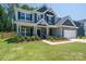 Beautiful two-story home featuring a manicured lawn, stone accents, and a welcoming covered front porch at 250 Winford Rd, Troutman, NC 28166