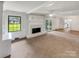 A cozy carpeted living room featuring a painted white fireplace and access to the kitchen and sunroom at 302 Melinda Ave, Kannapolis, NC 28083