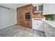 The kitchen features exposed brick wall, modern vent hood, and white cabinetry at 3800 Lovett Cir, Charlotte, NC 28210