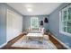 Light-filled living room featuring blue walls, a large window, and a seating area with a sofa and rug at 3800 Lovett Cir, Charlotte, NC 28210