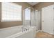 Bright bathroom featuring a soaking tub, separate glass shower, and a large window at 56119 Finches Ct, Indian Land, SC 29707
