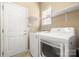 Functional laundry room with a front-load washer and dryer, built-in shelving, and neutral walls at 56119 Finches Ct, Indian Land, SC 29707