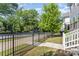 Exterior view showcasing a black metal fence, a small front lawn, mature trees, and a home's entrance at 635 R L Stowe Rd, Belmont, NC 28012