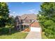 Beautiful two-story brick home featuring a manicured lawn, mature trees, and an attached garage at 1006 Apogee Dr, Indian Trail, NC 28079