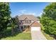Beautiful two-story brick home featuring a manicured lawn, mature trees, and an attached garage at 1006 Apogee Dr, Indian Trail, NC 28079