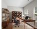 Well-lit home office with a desk, shelves, and an executive chair, creating a comfortable and productive workspace at 10446 Trolley Run Dr, Cornelius, NC 28031