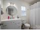 Clean bathroom features a round mirror over a white vanity, toilet, and shower with a white curtain at 1256 Canseco Ln, Hickory, NC 28602
