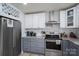 Modern kitchen featuring stainless steel appliances, white and gray cabinets, marble backsplash, and a wine rack at 1256 Canseco Ln, Hickory, NC 28602