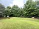 View of a large grassy backyard featuring mature trees and an iron fence at 1304 Ridge Haven Rd, Waxhaw, NC 28173