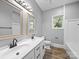 This large bathroom features double sinks, dark hardware, and a view of the backyard from the window at 144 Walnut St, Chester, SC 29706