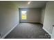 A well-lit bedroom with neutral walls, plush carpeting, and a large window for natural light exposure at 1459 Mocksville Hwy # 19, Statesville, NC 28625