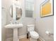 Charming powder room features pedestal sink, contemporary round mirror, and a toilet, showcasing stylish design at 148 Powder Spring Dr, Statesville, NC 28677
