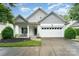 Charming home featuring white siding, a two-car garage, well-manicured landscaping and a cozy front porch at 18715 Coachmans Trce, Cornelius, NC 28031