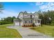 New gray home features three-car garage, manicured lawn, and a covered front porch at 277 Triple Ponds Ct, Clover, SC 29710
