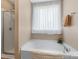Bright bathroom featuring a soaking tub under a window and separate glass enclosed shower at 4006 Centerview Dr, Indian Trail, NC 28079