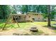 Spacious backyard featuring a swing set, brick fire pit, deck, screened-in porch, and lush landscaping at 411 Saint Andrews Rd, Statesville, NC 28625