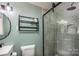 This bathroom has a glass shower door, a black metal rack, a sleek toilet, and light green colored walls at 411 Saint Andrews Rd, Statesville, NC 28625
