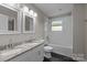 This renovated bathroom features a double vanity with granite counters and a tiled shower and tub at 5008 Unaka Ave, Charlotte, NC 28205
