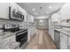 Open kitchen with stainless steel appliances, granite countertops, and wood-look floors flowing into the living space at 5008 Unaka Ave, Charlotte, NC 28205