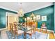 Elegant dining room features a glass top table, crystal chandelier, and rich teal walls at 517 Kingsdown Ct, Waxhaw, NC 28173