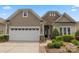 Charming home showcasing a manicured lawn, stone accents, and a white two-car garage door at 56113 Finches Ct, Indian Land, SC 29707