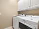 Bright laundry room featuring a white washer and dryer with overhead cabinets at 56113 Finches Ct, Indian Land, SC 29707