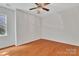 Empty bedroom with hardwood floors, ceiling fan and a bright window at 5963 Pale Moss Ln, Charlotte, NC 28269