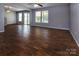 Spacious living room featuring wood-look flooring, modern ceiling fan, and large windows at 7623 Monarch Birch Ln, Charlotte, NC 28215