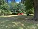 Spacious backyard with mature trees and two red storage buildings at 8616 Fallsdale Dr, Charlotte, NC 28214