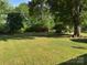 Expansive backyard featuring mature trees, a swing set, and two red storage buildings at 8616 Fallsdale Dr, Charlotte, NC 28214